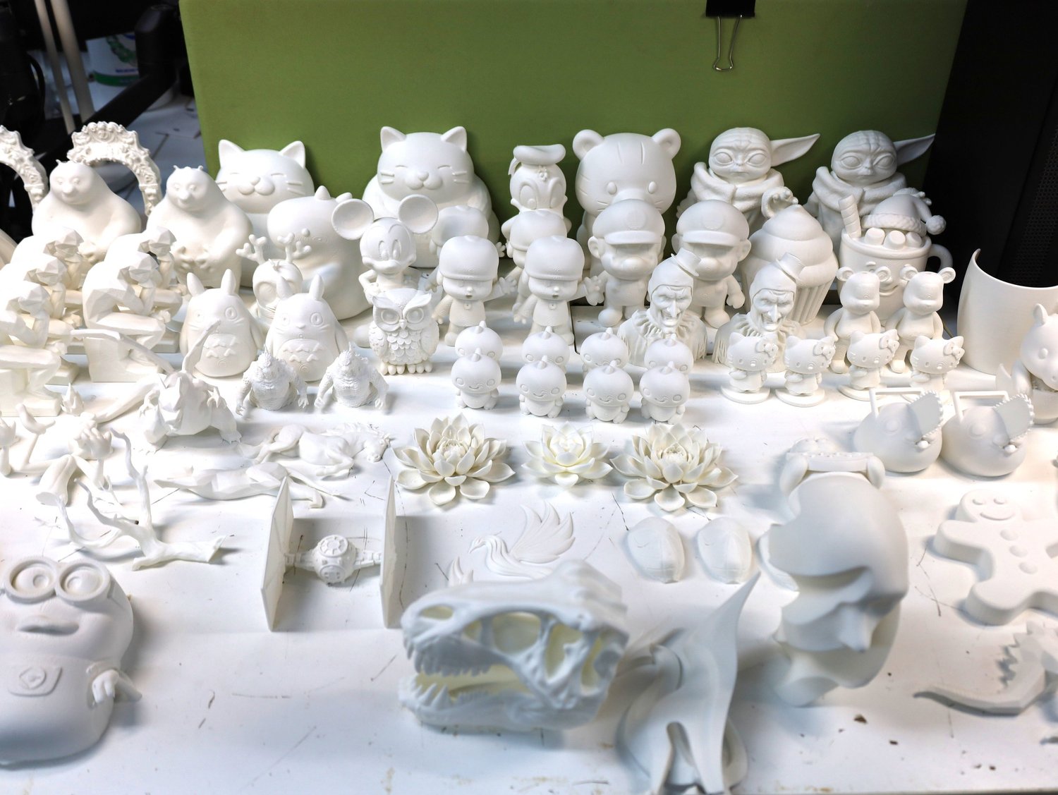 A tray of dozens of unpainted white 3D-printed figures to choose from