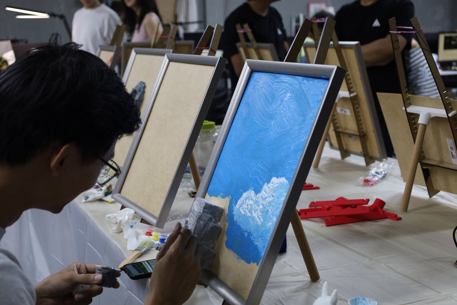 A corporate team painting 3D canvases together at rows of easels in the COLORVERSE studio