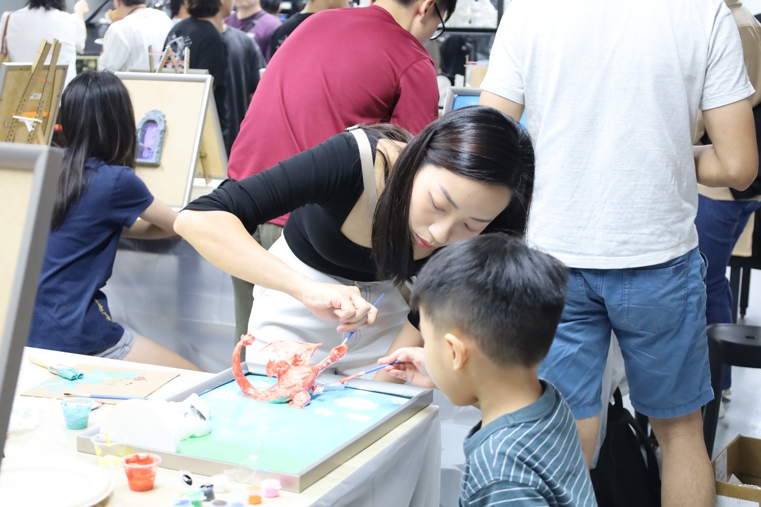 Guests of different ages painting 3D figures together at a group art jamming session
