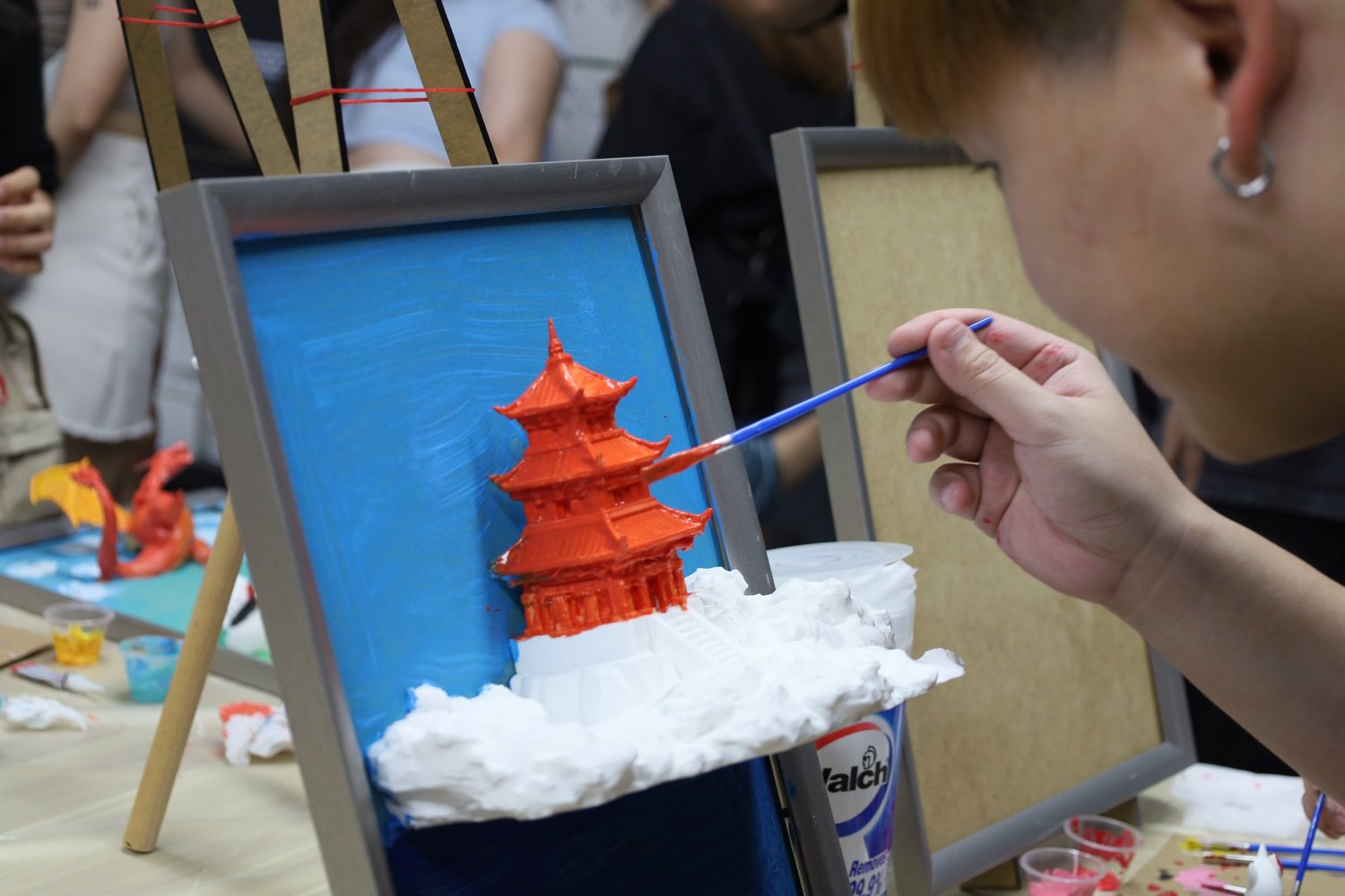 A guest painting a red 3D-printed pagoda mid-session
