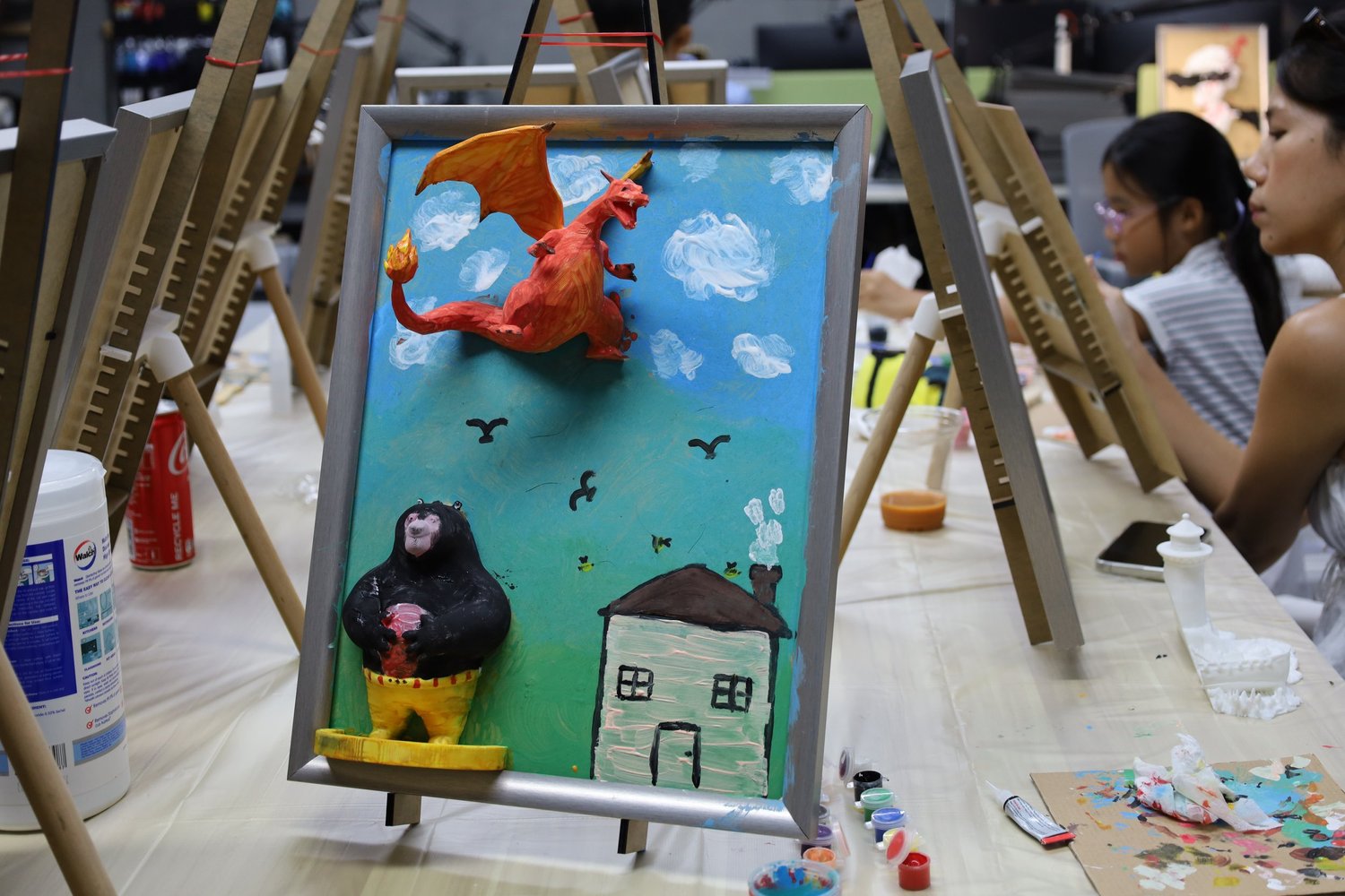 A guest smiling with a 3D figure in the busy studio