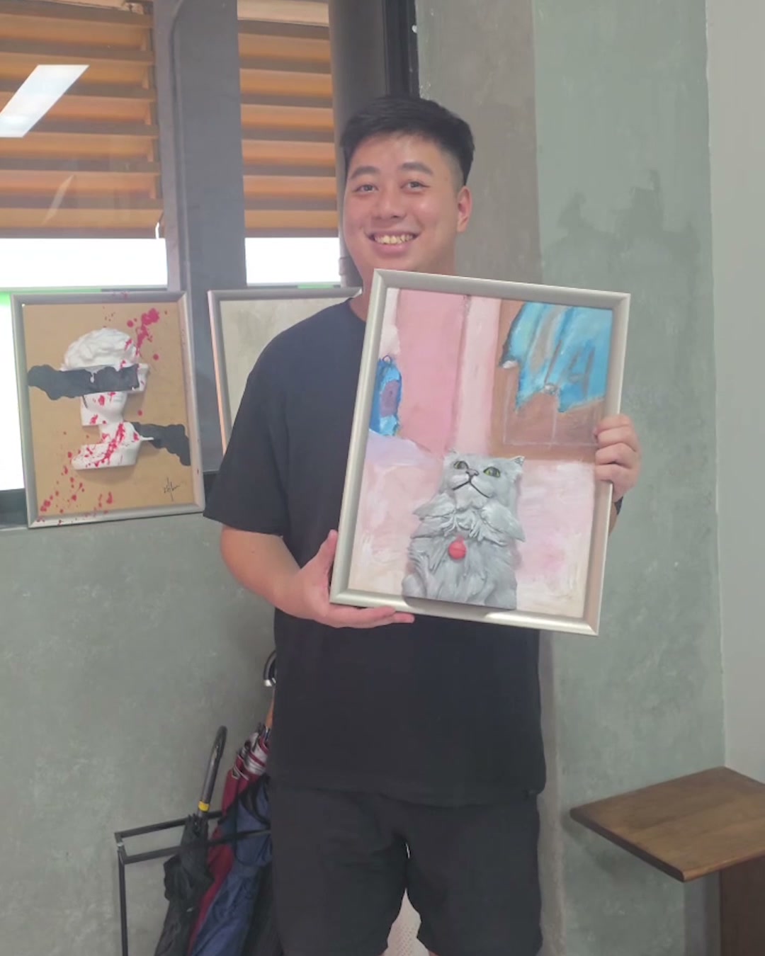 A guest smiling and holding up the finished framed cat canvas